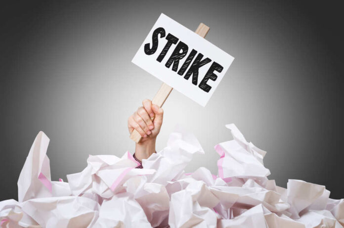 shutterstock_1285949986.jpg featured image Hand holding strike sign amid crumpled paper pile