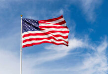 American flag waving against a blue sky.