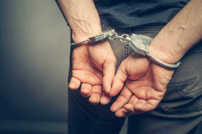 shutterstock_437224012.jpg featured image Person with handcuffs behind their back.