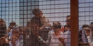 Group of people behind a wire fence.