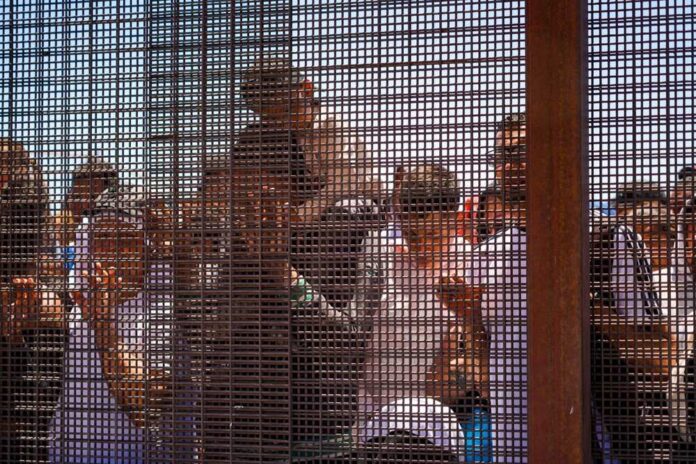 Group of people behind a wire fence.