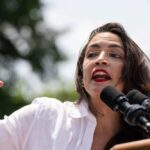 Alexandria Ocasio-Cortez speaking at an outdoor event.