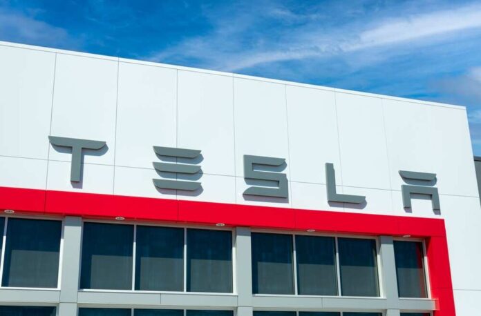 shutterstock_2500278999.jpg featured image Tesla building with logo against blue sky