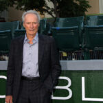 Man in suit standing in front of green seats