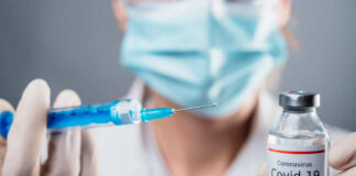 Doctor holding COVID-19 vaccine vial and syringe.
