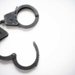 Open metal handcuffs on white background.