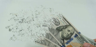 Hundred dollar bills disintegrating in hand