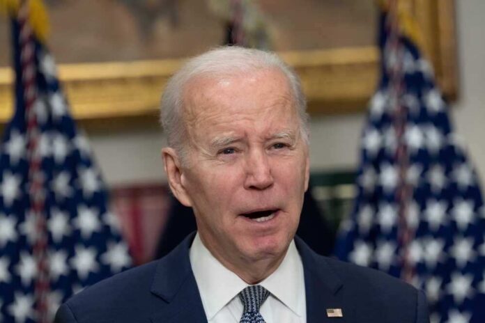 Man speaking with American flags in the background.