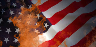 American flag partially set on fire with orange flames