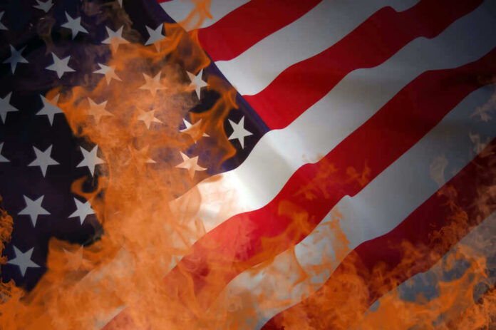 American flag partially set on fire with orange flames