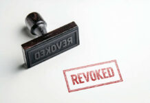 Wooden stamp next to red revoked text stamp