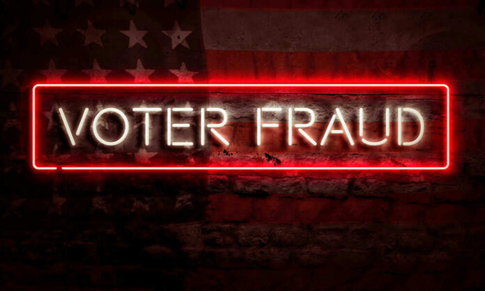 Neon sign reading Voter Fraud on American flag background.