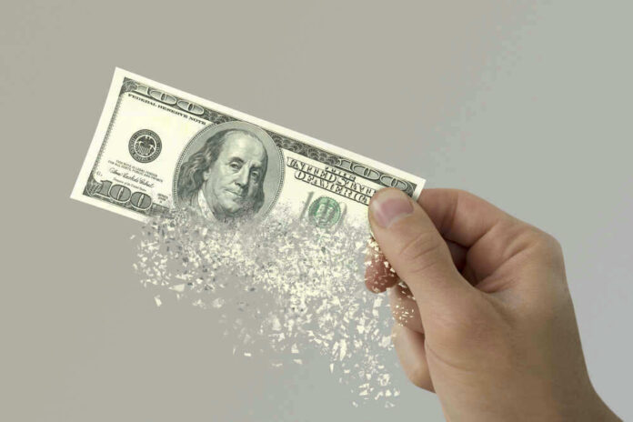 Hand holding a disintegrating hundred dollar bill