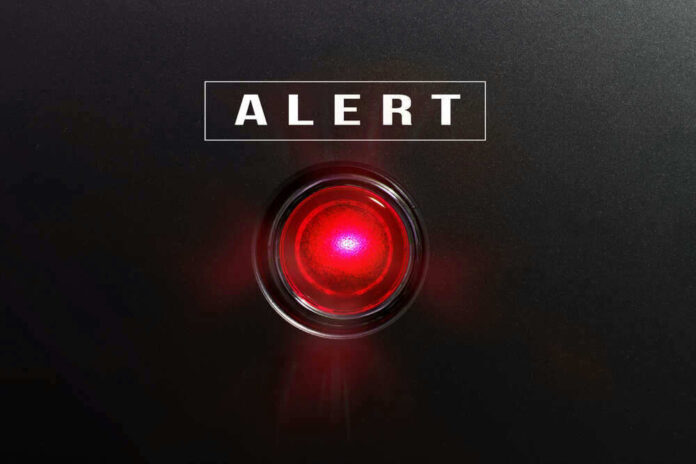 Red alert light against black background, text ALERT