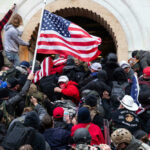 Crowd storming a building, waving an American flag