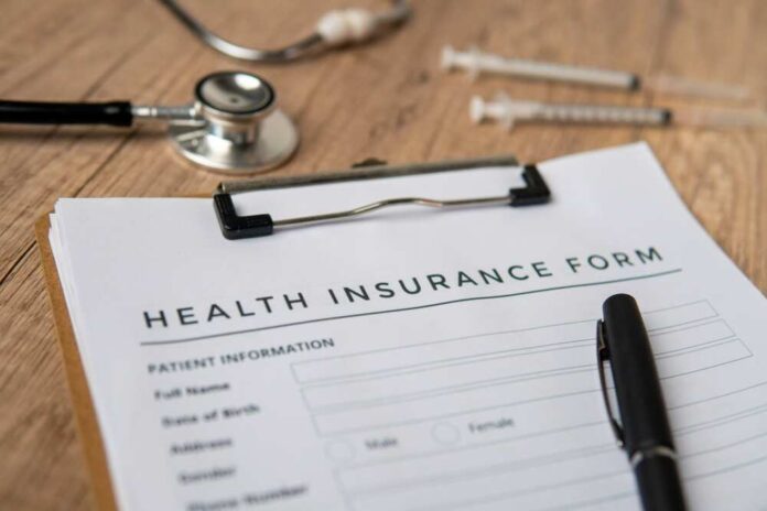 Health insurance form with a pen, stethoscope, and syringes on a wooden surface