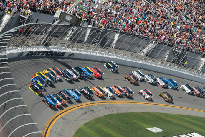 Race cars on Daytona track with large audience watching