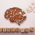GOP Icon’s Dementia Announcement Stuns Colleagues Wooden brain illustration with puzzle pieces and the word DEMENTIA spelled out in blocks
