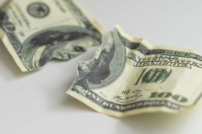 Torn and crumpled hundred dollar bills on a white surface