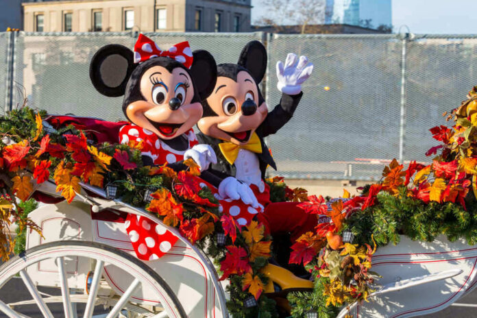 Mickey and Minnie Mouse waving from decorated carriage.