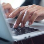Remote Work CRUSHED — Major Retailer Takes Action Close-up of hands typing on a laptop keyboard