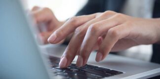 Close-up of hands typing on a laptop keyboard