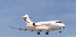 A private jet descending towards the runway against a blue sky