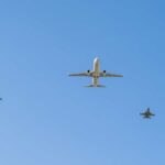 A commercial airplane flying above two military jets in a clear blue sky