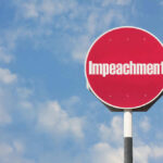 Red sign with the word Impeachment against sky