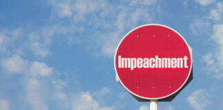 Red sign with the word Impeachment against sky