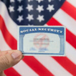 Social Security COLLAPSES in 2032?! Hand holding social security card, American flag background.