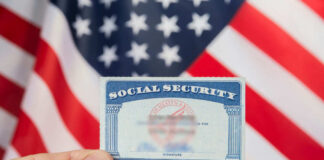 Hand holding social security card, American flag background.