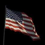American flag waving against a black background.