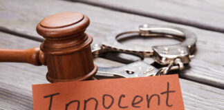 A wooden gavel next to handcuffs and a card that says 'Innocent'