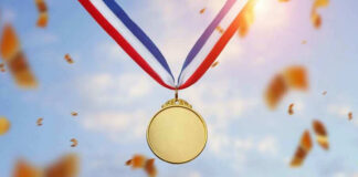 Gold medal with blue, white, red ribbon, sky background.