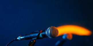 Close-up of a microphone on a stand, dark background.