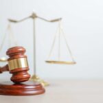 Courtroom ERUPTS — Trump Attempted Assassin’s Shocking Behavior A wooden gavel in front of a balance scale symbolizing justice