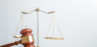 A wooden gavel in front of a balance scale symbolizing justice
