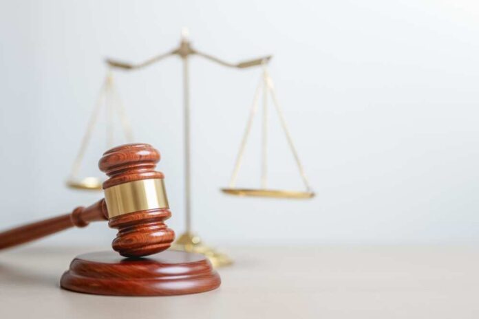 A wooden gavel in front of a balance scale symbolizing justice