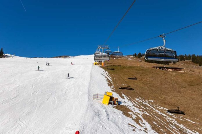 Ski lift transporting skiers up a snowy slope under a clear blue sky