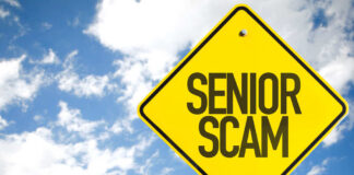 Yellow warning sign displaying 'SENIOR SCAM' against a blue sky