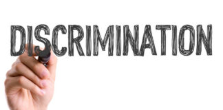 A hand holding a marker writing the word 'DISCRIMINATION'