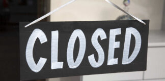 A black sign with the word 'CLOSED' painted in white letters
