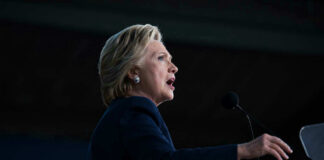 Hillary Clinton speaking at podium with a microphone.