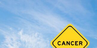 Yellow warning sign displaying the word 'CANCER' against a blue sky