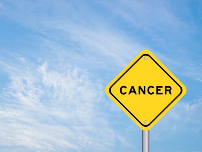 Yellow warning sign displaying the word 'CANCER' against a blue sky