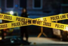 Police tape marking a crime scene with blurred figures in the background