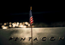 American flag above engraved Pentagon sign at night