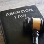 A gavel resting on a book titled 'Abortion Law'