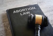 A gavel resting on a book titled 'Abortion Law'